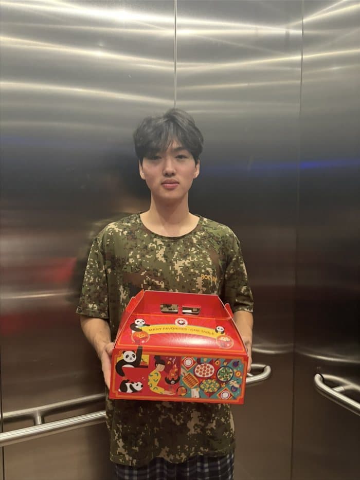 Brandon holding a Panda Express family meal box in an elevator