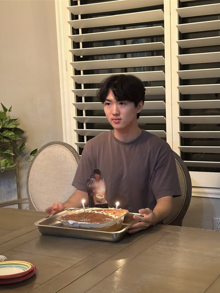Brandon with a birthday cake and two lit candles
