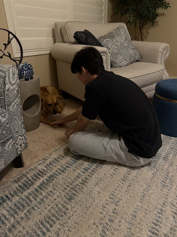 Brandon holding paws with a dog in the living room